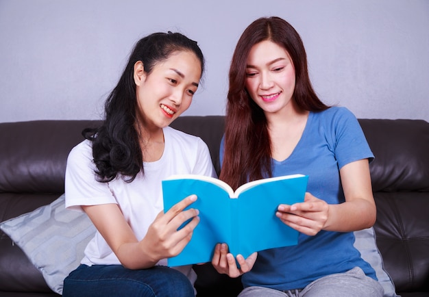 twee vrouw die een boek op bank in woonkamer thuis leest