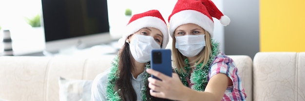 Twee vrouw in beschermend masker nemen selfie op telefoon.