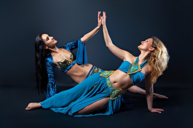 Twee vrouwelijke buikdanseressen die blauwe kostuums dragen