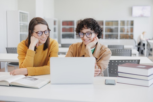 Twee vrouwelijke collega's werken op laptops in de online trainingswebinar van de coworking office-bibliotheek