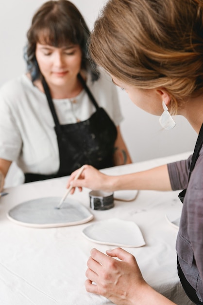 Twee vrouwelijke keramist werken door handen in aardewerk studio.