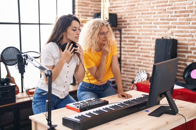 Twee vrouwelijke muzikanten componeren een lied met behulp van toetsenbord in de muziekstudio
