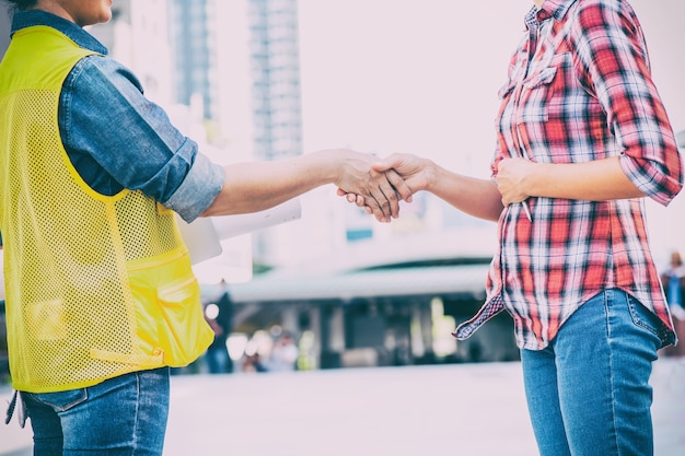 Twee vrouwelijke werknemers die elkaar de hand schudden