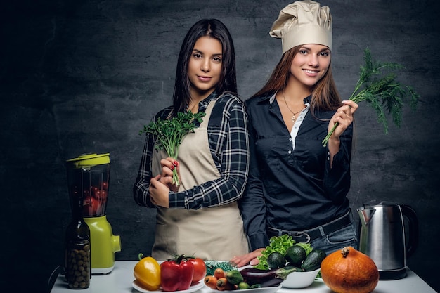 Twee vrouwen bereiden groentesap in een blender op een donkere achtergrond.