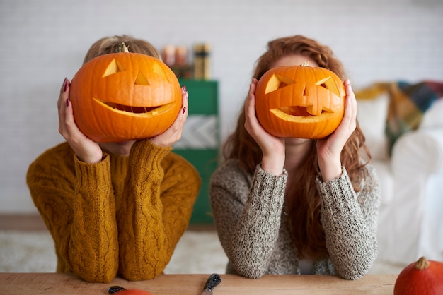 Twee vrouwen die Halloween-pompoenen tonen