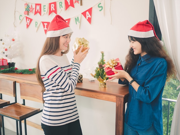 Twee vrouwen die van Azië giftdoos in Kerstmispartij houden