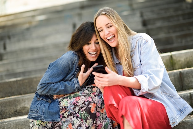 Twee vrouwen die wat grappig ding op hun slimme telefoon bekijken