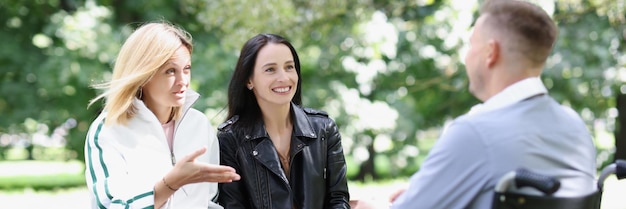 Twee vrouwen en een man in een rolstoel communiceren in het concept voor collaboratief afstandsonderwijs in het park