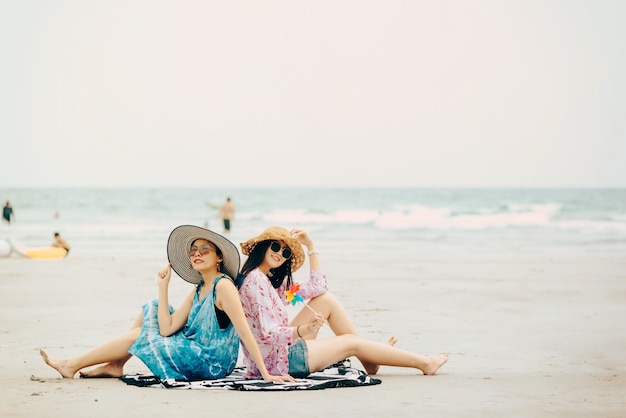 Twee vrouwen genieten van strand ontspannen blij in de zomer door tropisch blauw water. Model op reis die strandhoed draagt.