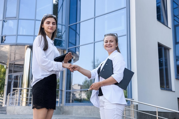 Twee vrouwen handenschudden buiten het grote zakencentrum. Succesvolle vrouwen die een deal sluiten