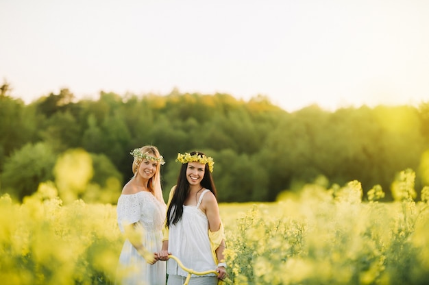 Twee vrouwen in een koolzaadveld met een fiets genieten van een vreugdevolle wandeling in de natuur.