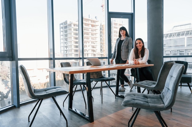 Twee vrouwen in formele kleding zijn binnen in het moderne kantoor werkt samen