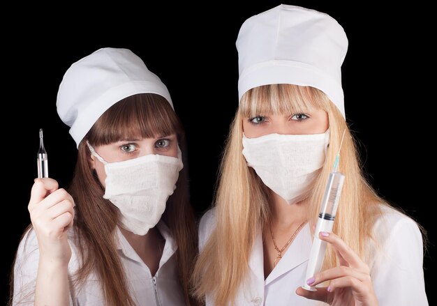 twee vrouwen in witte uniformen met een spuit in hun handen