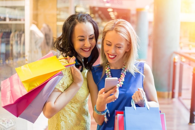 Twee vrouwen kijken naar de smartphone tijdens het winkelen