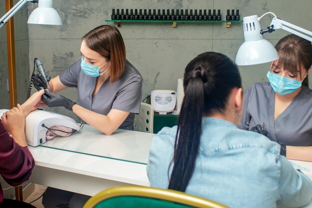 Twee vrouwen krijgen een manicure door twee manicure in een schoonheidssalon