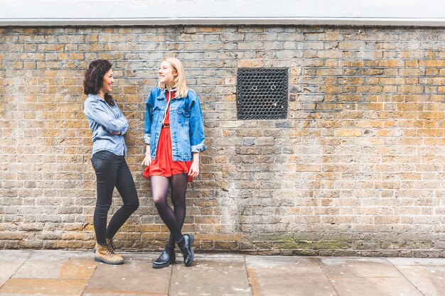 Twee vrouwen leunend op een muur en praten in Londen