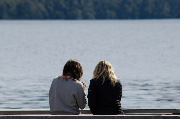 twee vrouwen met hun rug naar een meer op een pier vrienden op vakantie in Patagonië