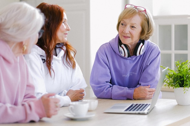 twee vrouwen met koptelefoon zitten aan een tafel met een laptop