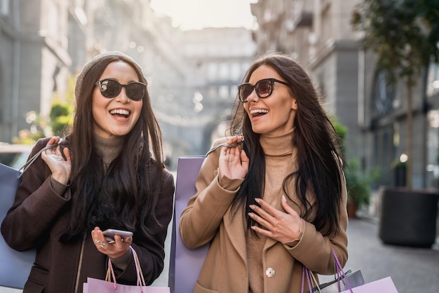 Twee vrouwen op straat in de stad die plezier hebben na het winkelen