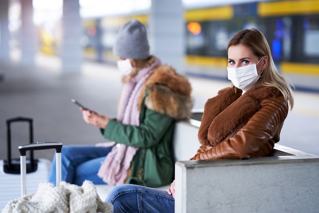 Twee vrouwen op treinstation die maskers dragen vanwege covid-19-beperkingen