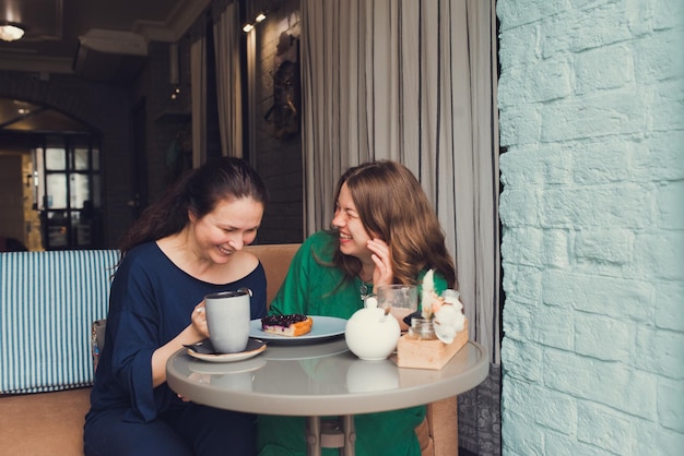 Twee vrouwen praten en drinken koffie in café