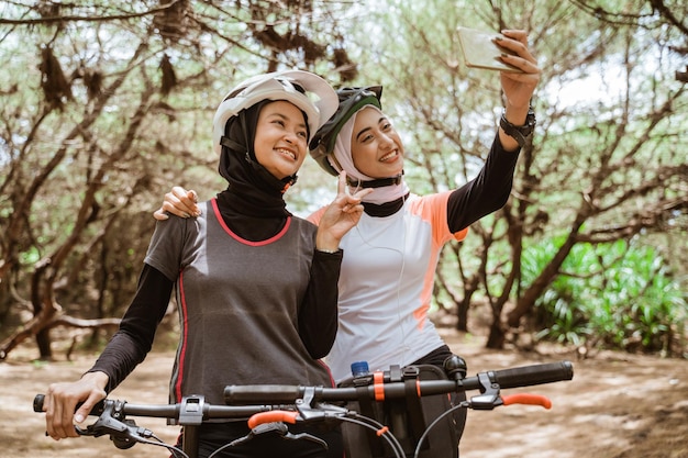 Twee vrouwen selfie met v-teken handgebaar tijdens het fietsen