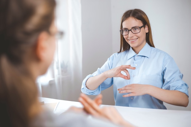 Twee vrouwen spreken gebarentaal. Meisjes die de taal spreken van slechthorende mensen, doven.