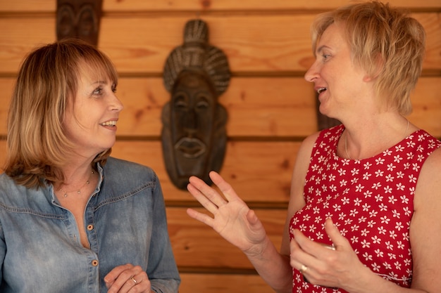 Foto twee vrouwen van 55 jaar kijken elkaar aan en lachen hartelijk en praten