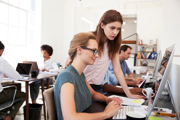 Twee vrouwen werken samen op de computer in een open kantoor