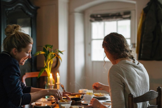 Twee vrouwen zitten aan een tafel en eten bij kaarslicht