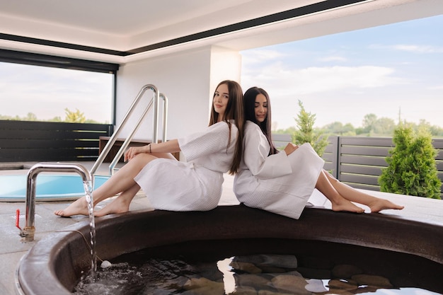 Twee vrouwen zitten in een bubbelbad, een van hen draagt witte gewaden en de andere draagt witte gewaden.