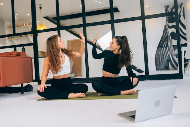 Twee vrouwen zittend in lotushouding geven een high five