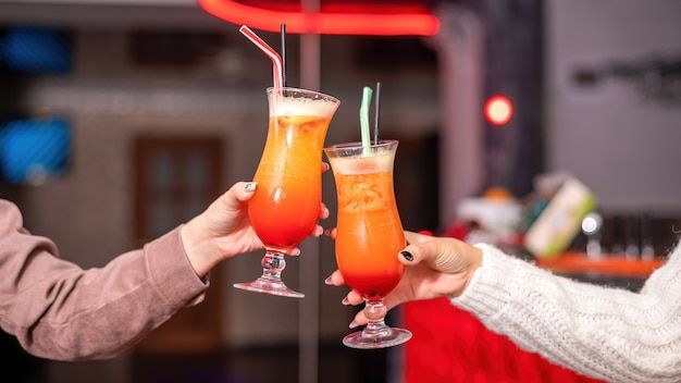 Twee vrouwenhanden rammelende glazen met cocktails in een restaurant