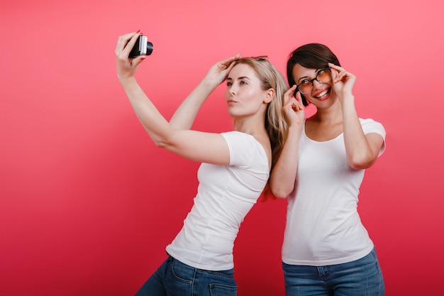 Twee vrouwenvrienden die in de studio stellen - neem een selfiefoto, grappige tijd.