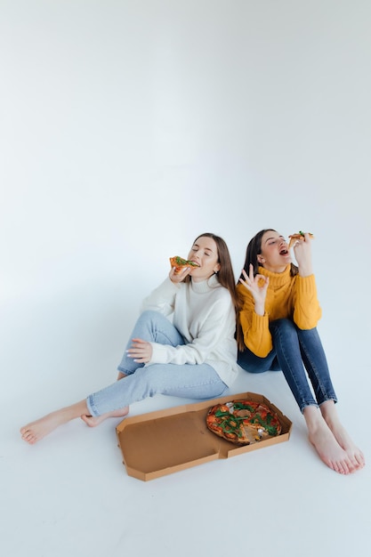 Twee vrouwenvrienden die pizza eten.