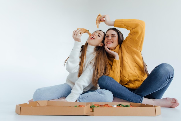 Twee vrouwenvrienden die pizza eten.