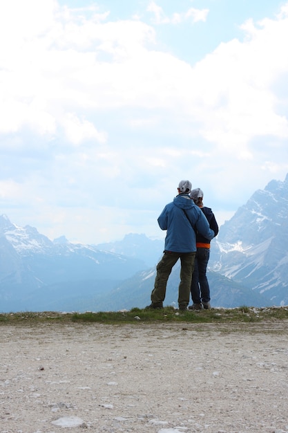 Twee wandelaars staan op een rots en kijken naar de bergen
