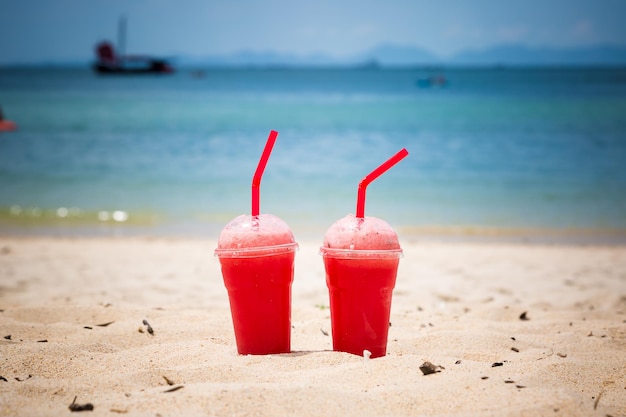 Twee watermeloen-smoothies in plastic wegwerpbekers met tubes tropisch strandlevensstijl verfrissend