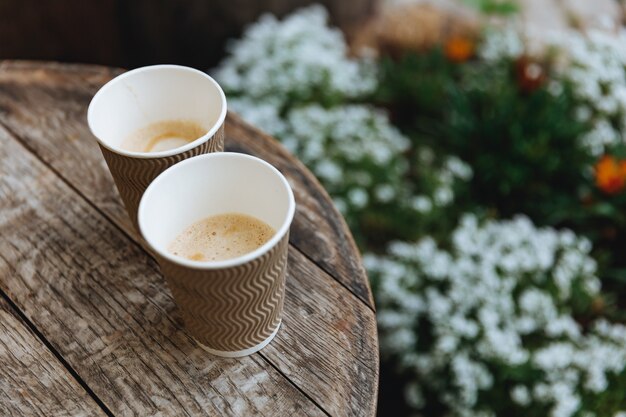 Twee wegwerp bruine kopjes gevuld met vers gezette koffie geserveerd op houten tafel