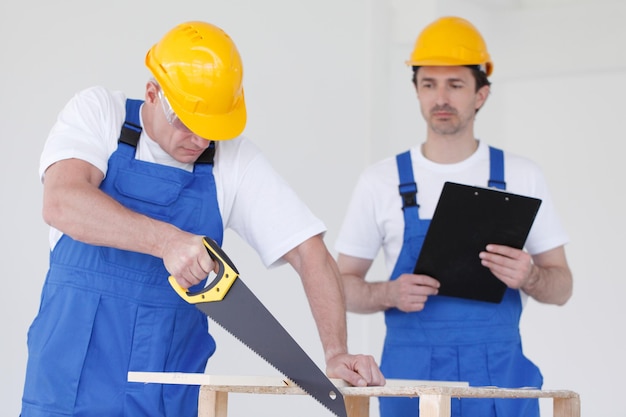 Twee werklieden die houten plank zagen