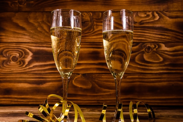 Twee wijnglazen met champagne en gouden lint op rustieke houten tafel