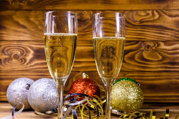 Twee wijnglazen met champagne en verschillende kerstversieringen op houten tafel