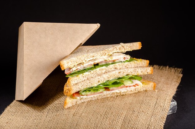 twee witbroodsandwiches liggen naast de jute, zwarte achtergrond