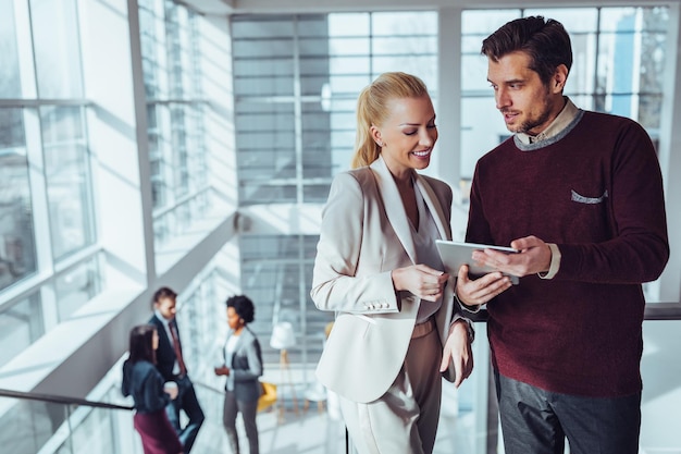 Twee zakelijke collega's staan met een digitale tablet en discussiëren over werk