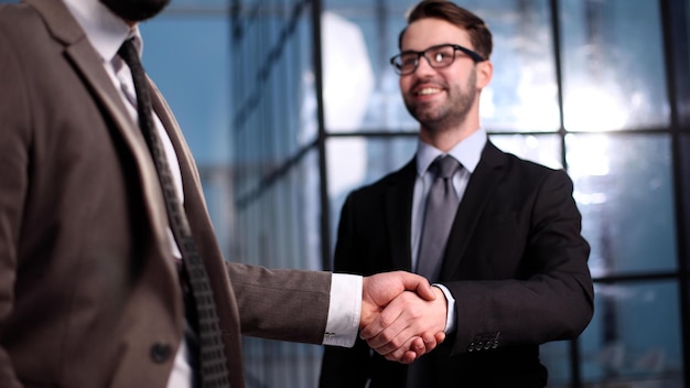 Twee zakenlieden schudden elkaar de hand en sluiten een deal in een kantoorgang