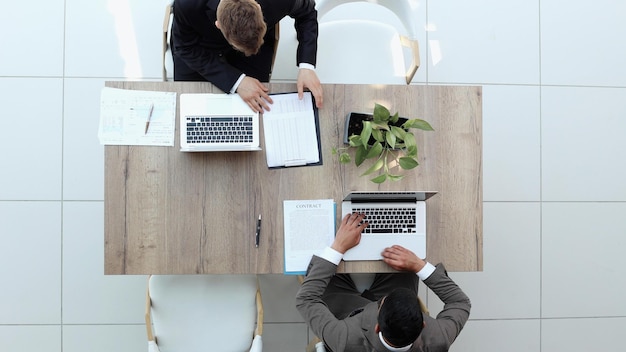 twee zakenlieden zitten op een stoel en kijken naar iets op een laptop