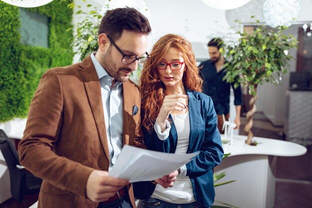 Twee zakenmensen in een serieuze discussie staan samen op kantoor en kijken naar het businessplan.