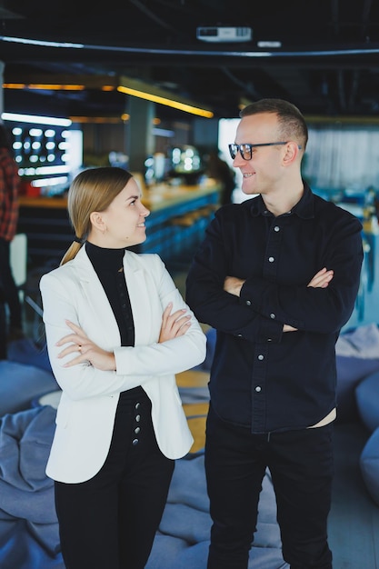 Twee zakenmensen, man en vrouw, staan in een modern kantoor en poseren voor de camera