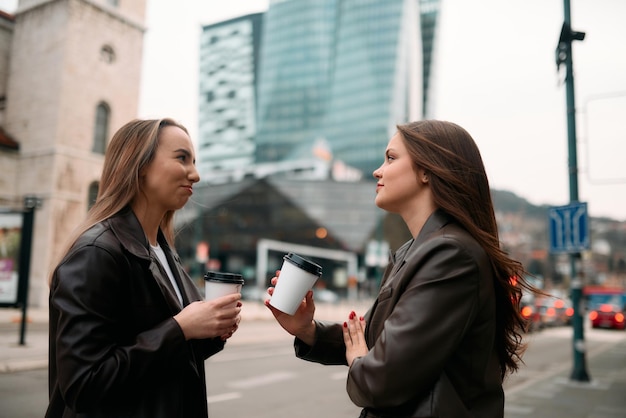 Foto twee zakenvrouwen nemen een pauze buiten hun bedrijf en genieten van een moment van ontspanning terwijl ze