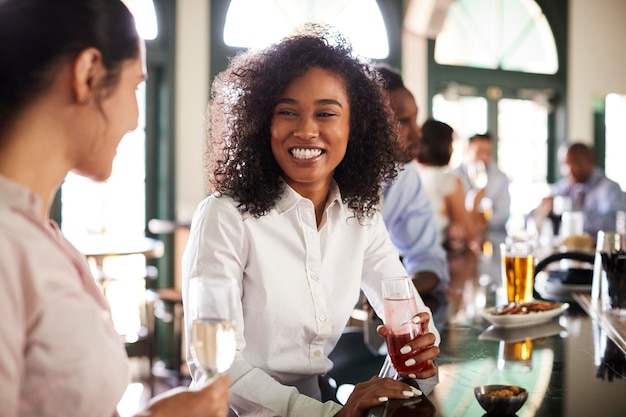 Twee zakenvrouwen ontmoeten elkaar voor een drankje na het werk in de bar